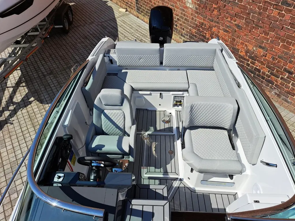 Top view of a modern boat interior featuring gray upholstered seating, a steering wheel, and a sleek design.